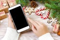 Female buyer makes order at screen of smartphone with copy space. Christmas online shopping. Woman buys presents for Royalty Free Stock Photo
