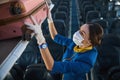 Airline stewardess carefully putting pink suitcase into luggage rack Royalty Free Stock Photo