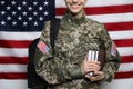 Female cadet with backpack and books against American flag, closeup. Military education Royalty Free Stock Photo