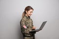 Female cadet with laptop on light grey background. Military education