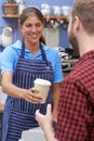 Female Cafe Worker Serving Customer With Takeaway Coffee