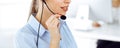 Female call operator is using computer and headset for consulting clients online, close-up. Group of diverse people Royalty Free Stock Photo