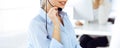Female call operator is using computer and headset for consulting clients online, close-up. Group of diverse people Royalty Free Stock Photo
