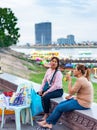 Female Cambodian food stall sellers,sit along the river wall,at Phnom Penh\'s popular Sisowath Quay area at dusk