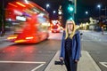 Female with camera as motion blurred red London Double Decker buses pass at night Royalty Free Stock Photo