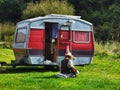 Female camper playing guitar near old small caravan in New Zealand