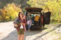 Female camper with sleeping bag near car outdoors.