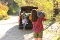 Female camper with sleeping bag near car outdoors.