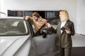 Female car dealer standing with client of dealership in showroom. Royalty Free Stock Photo