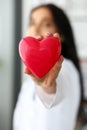 Female cardiolog holding in arms red toy heart