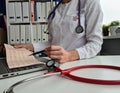 Female cardiologist checking cardiogram of patient with pen in hand