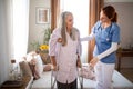 Female caregiver helping senior woman to walk with crutches in her home. Royalty Free Stock Photo