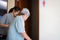 Female caregiver is helping support elderly woman walk into the restroom carefully,asian senior with bladder control problem need Royalty Free Stock Photo