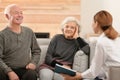 Female caregiver reading book to elderly spouses