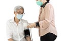 Female caregiver using automatic blood pressure monitor,checking health,measuring blood pressure and rate of the heartbeat of old