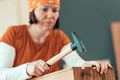 Female carpenter hammering nail into wooden crate