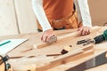 Female carpenter manually sanding wooden plank