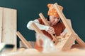 Female carpenter repairing wooden chair seat in workshop