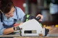 A female carpenter uses a chainsaw while working in a wood shop