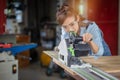 A female carpenter uses a chainsaw while working in a wood shop