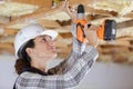 Female carpenter using drill on wood structure