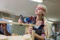 Female carpenter wear goggles using woodworking drill to make furniture. carpenter woman using electric drill machine at workplace