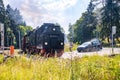 Female and cars standing while Harz locomotive passes through railway lines