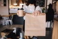 Female cashier with face mask serving coffee and food to customer, shop open after lockdown. Woman hold packege with Royalty Free Stock Photo