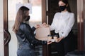 Female cashier in face mask serving coffee and package with food to customer. Coffee shop open after lockdown. Woman Royalty Free Stock Photo