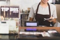 Female cashier operating cash register with order in her hand in cafe.