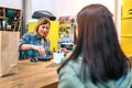 Female cashier passing credit card through store terminal to charge purchased items by customer Royalty Free Stock Photo