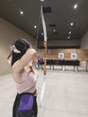 A female casual hobbyist doing target practice at an indoor archery range Royalty Free Stock Photo