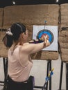 A female casual hobbyist takes off the arrows from an Archery Target Face Sheet at an indoor archery range Royalty Free Stock Photo