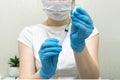 Female doctor in protective blue gloves hold medicine syringe with vaccine on white background. Concept of vaccination and Royalty Free Stock Photo