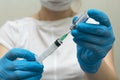 Female doctor in protective blue gloves hold medicine syringe with vaccine on white background. Concept of vaccination and Royalty Free Stock Photo