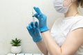 Female doctor in protective blue gloves hold medicine syringe with vaccine on white background. Concept of vaccination and Royalty Free Stock Photo