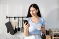 Female caucasian drinking morning coffee reading message smartphone sitting on modern kitchen counter. woman breakfast social Royalty Free Stock Photo