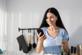 Female caucasian drinking morning coffee reading message smartphone sitting on modern kitchen counter. woman breakfast social Royalty Free Stock Photo