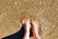 Female caucasian feet standing in sea. Top view. Summer vacation and tourism concept