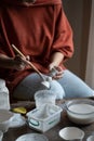 Female ceramicist or potter holding paintbrush applying glaze on ceramic pieces Royalty Free Stock Photo