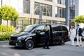 Female chauffeur waits a business people near minivan taxi