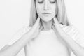 Female checking thyroid gland by herself. Close up of woman in white t- shirt touching neck with red spot. Thyroid