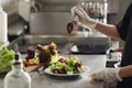 Female chef adding sauce to cooking food in restaurant kitchen Royalty Free Stock Photo