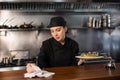 Female chef checks the prepared dish with the paid check in kitchen of the restaurant Royalty Free Stock Photo