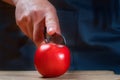 Female Chef cuts one red tomato with a knife on wooden cutting board.