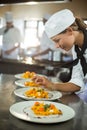 Female chef garnishing plate of food Royalty Free Stock Photo