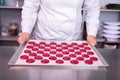 Female chef holding baking pan with colorful biscuits