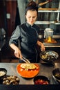 Female chef with pan cooking meat with pasta Royalty Free Stock Photo