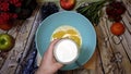 Female chef pouring milk in a bowl, pancake preparation, top view