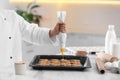 Female chef preparing biscuits at kitchen table. Cooking delicious food